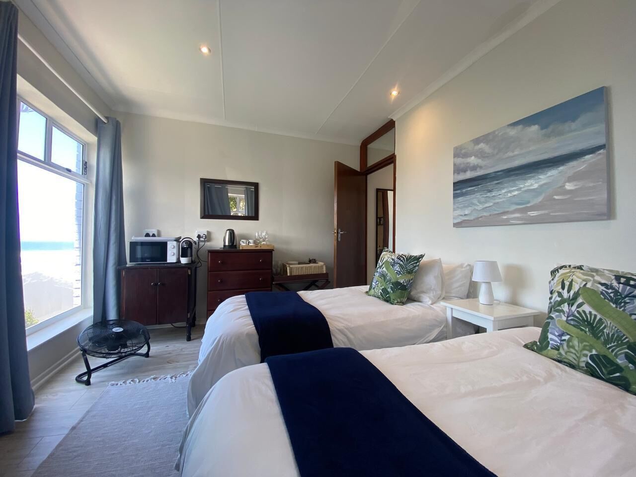 Habitación de hotel con dos camas, un escritorio, un microondas, un armario pequeño y una ventana con cortinas.