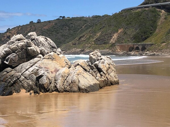 Na praia, areia branca, espreguiçadeiras, guarda-sóis 