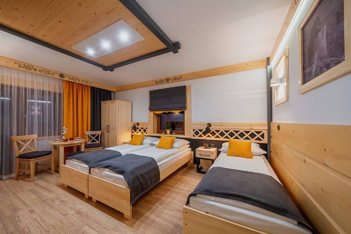 Une chambre d’hôtel avec deux lits, un bureau, une armoire et une grande fenêtre avec des rideaux.