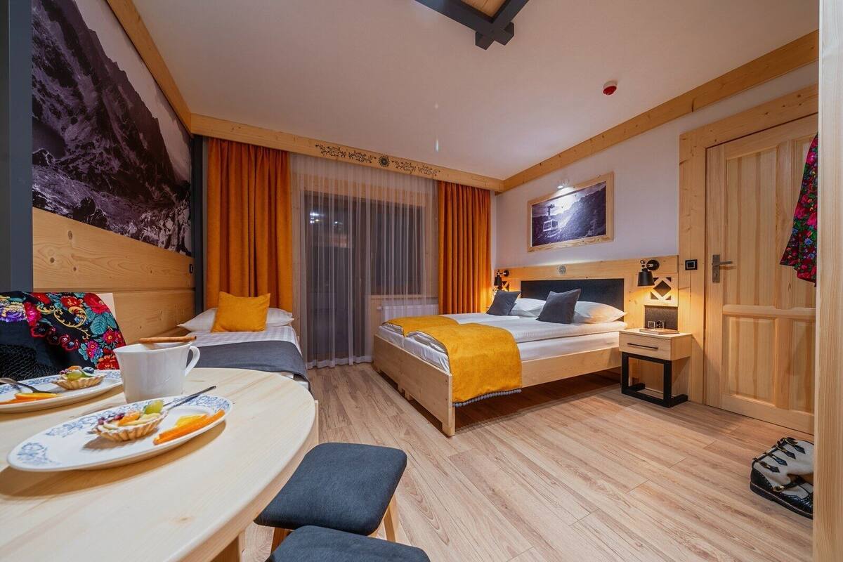 Une chambre d’hôtel avec deux lits, un bureau, une chaise, une table avec une assiette de nourriture et une porte.