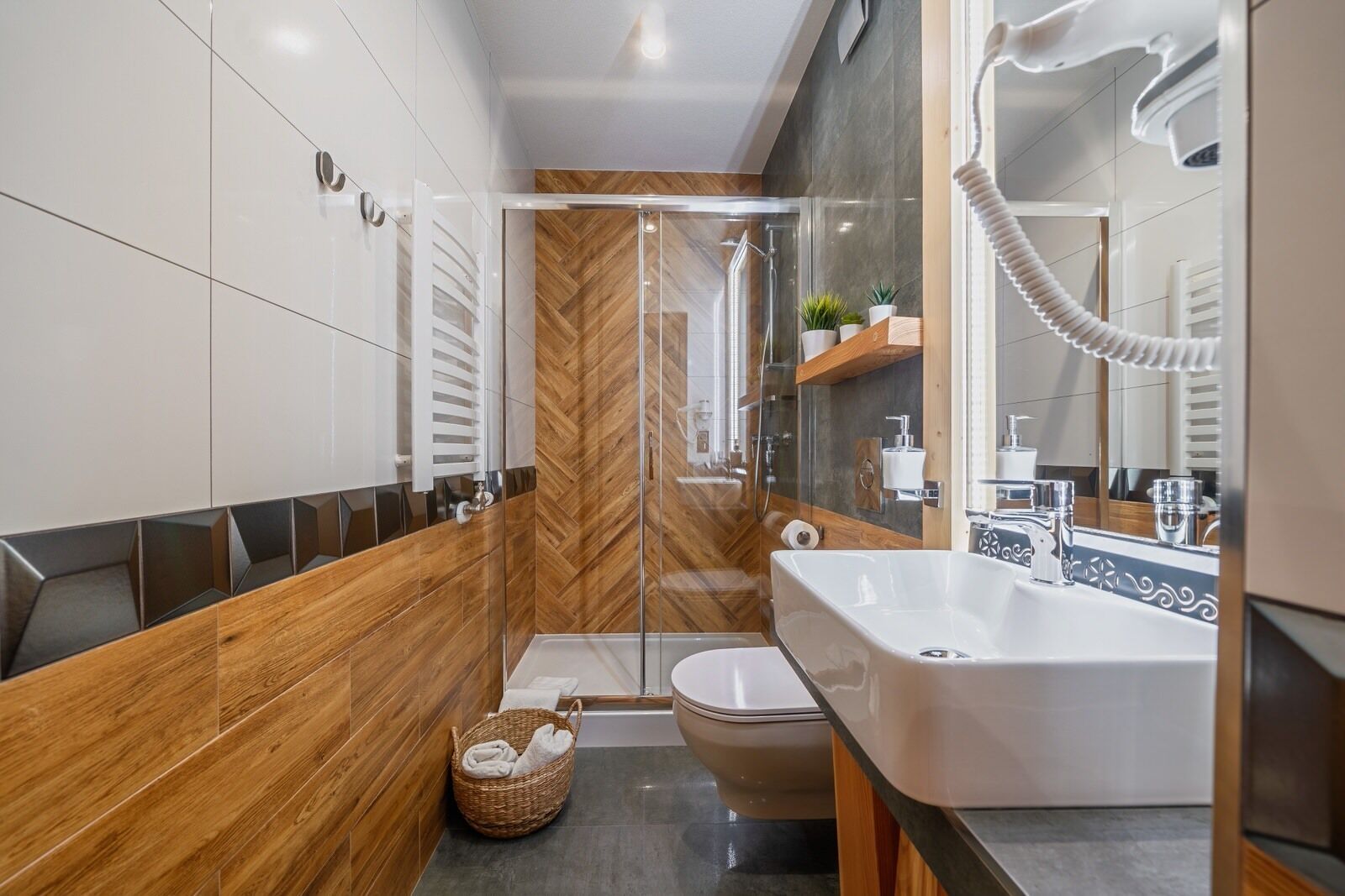 A modern bathroom with a large sink, a glass shower enclosure, and a wooden vanity.