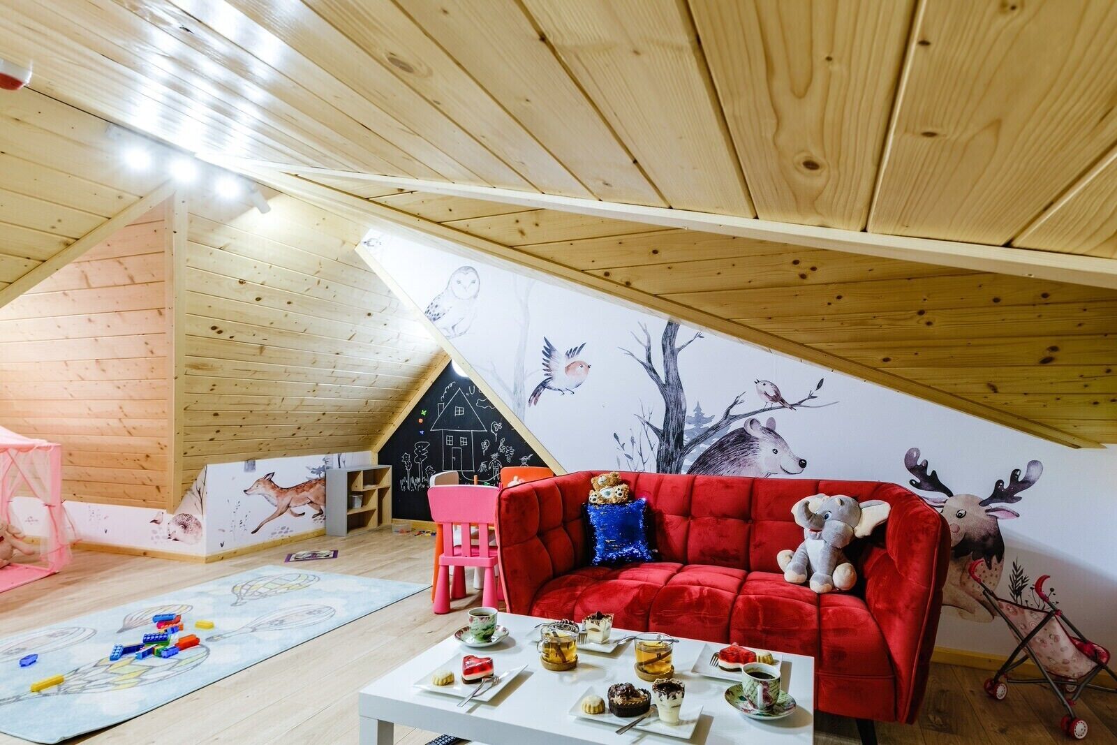 A cozy attic room with a sloped ceiling, wooden walls, and a mural of animals.