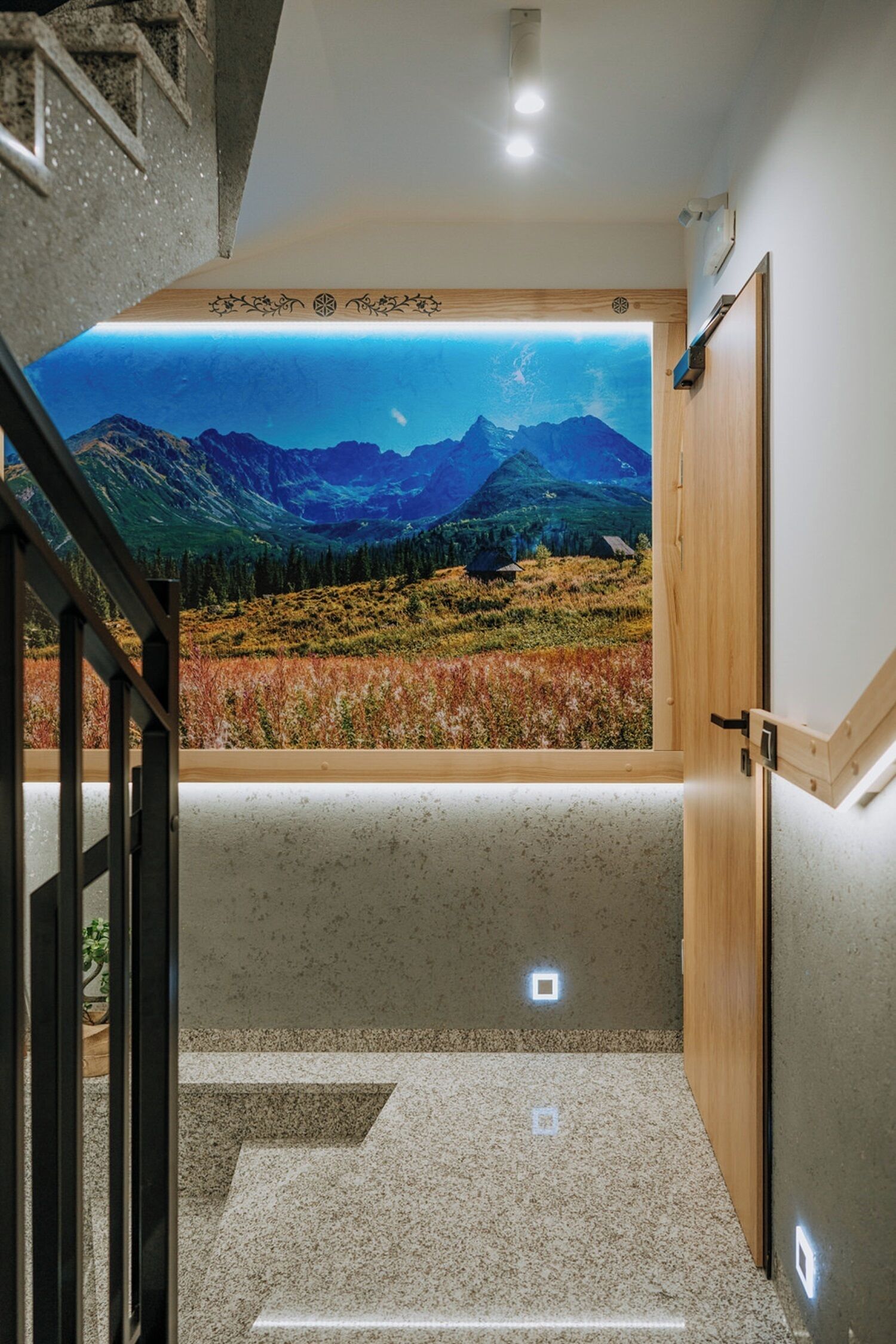 A staircase leading to a room with a large window offering a view of mountains and a lake.