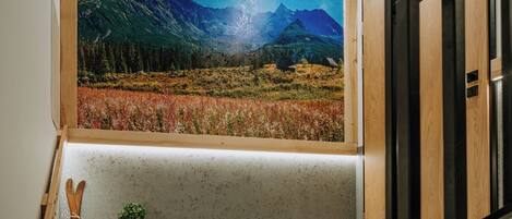 A room with a large window displaying a mountainous landscape.