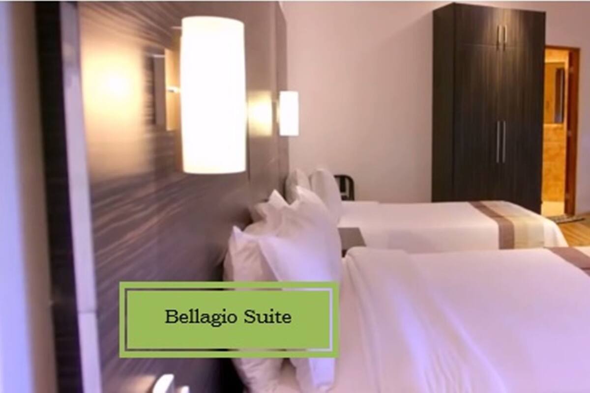 Eine Bellagio-Suite mit zwei Betten, einem dunklen Wandschrank, einer Sitzecke mit Sofa und Tisch und einem großen Fenster.