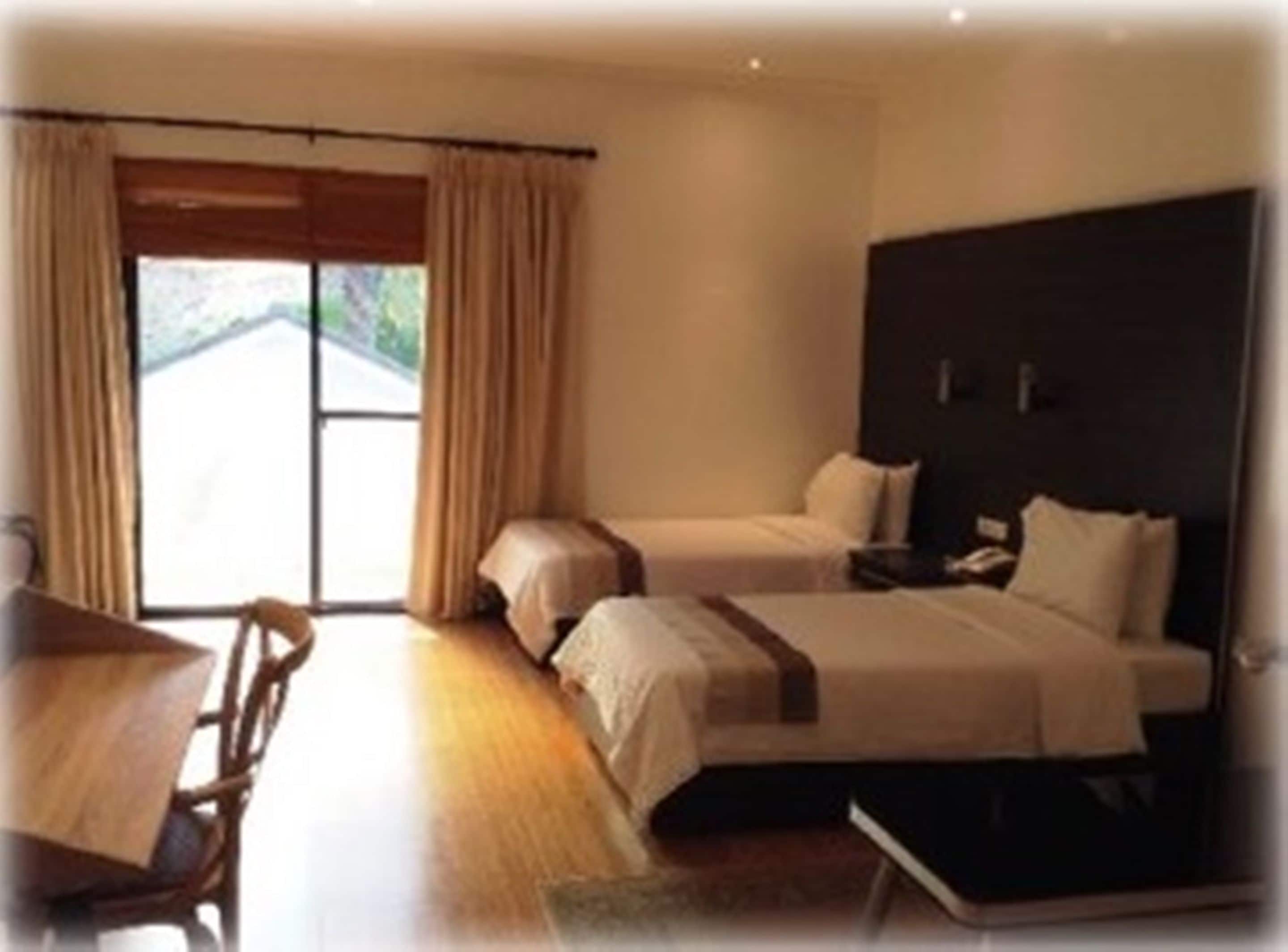 A hotel room with two beds, a desk, and a chair.