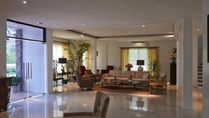 A spacious living room with a glass coffee table, a sofa set, and a dining area with a glass table. - Bellagio Hills Hotel and Restaurant (Paoay)