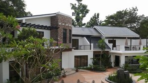 A modern two-story house with a stone facade, a covered patio with outdoor furniture, and a landscaped garden area. - Bellagio Hills Hotel and Restaurant (Paoay)
