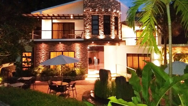 A modern two-story house with a stone facade, outdoor seating area, and a well-lit entrance. - Bellagio Hills Hotel and Restaurant (Paoay)
