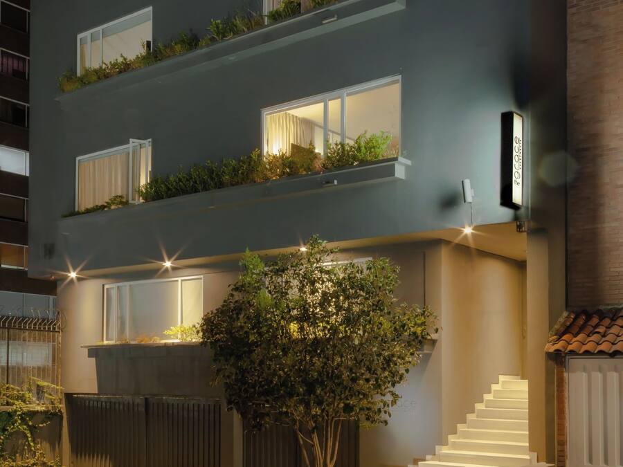 A multi-story building with balconies, a staircase, and a tree in the foreground.
