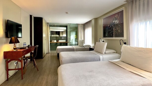 A hotel room with two beds, a desk with a chair, a TV, and a bathroom visible in the background. - The Grace Hotel (Bogotá)