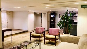 A modern lobby with two pink armchairs, a beige sofa, a glass coffee table, and a potted plant. - The Grace Hotel (Bogotá)