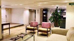 A modern lobby with two pink armchairs, a beige sofa, a glass coffee table, and a potted plant. - The Grace Hotel (Bogotá)