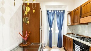 A kitchen with wooden cabinets, a gas stove, a sink, and a glass table. - La dolce vita QG (Rome)