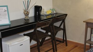 A compact kitchenette with a refrigerator, a coffee maker, and a small table with a tray of condiments. - La dolce vita QG (Rome)