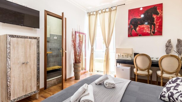 A hotel room with a bed, a desk, a chair, a TV, a cabinet, and a window with curtains. - La dolce vita QG (Rome)