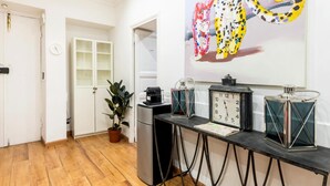 A room with a wooden floor, a refrigerator, a coffee machine, a clock, and a potted plant. - La dolce vita QG (Rome)