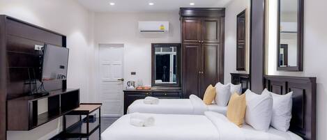 A hotel room with two beds, a TV, a wardrobe, and a mirror.