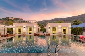 A poolside area with two buildings, a clear sky, and a hilly landscape in the background. - T Villas Huahin (Hua Hin)