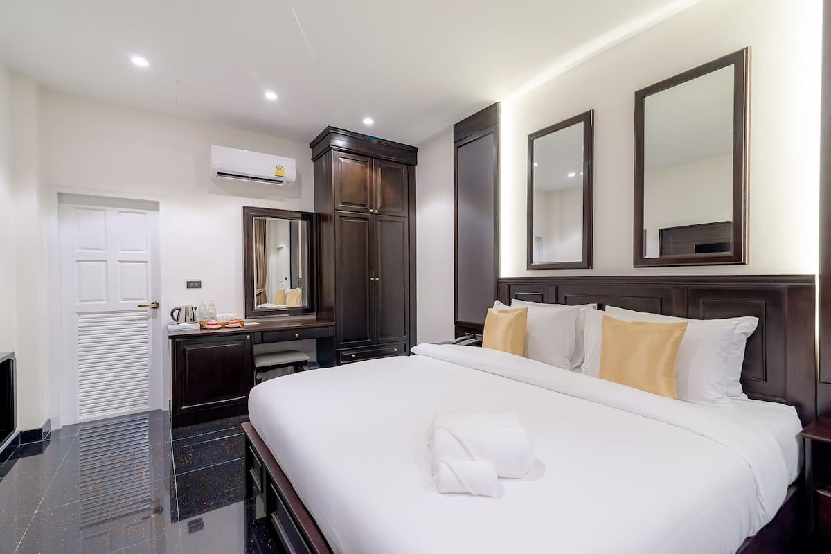 Une chambre d’hôtel avec un grand lit, une armoire, un miroir et un appareil de climatisation.