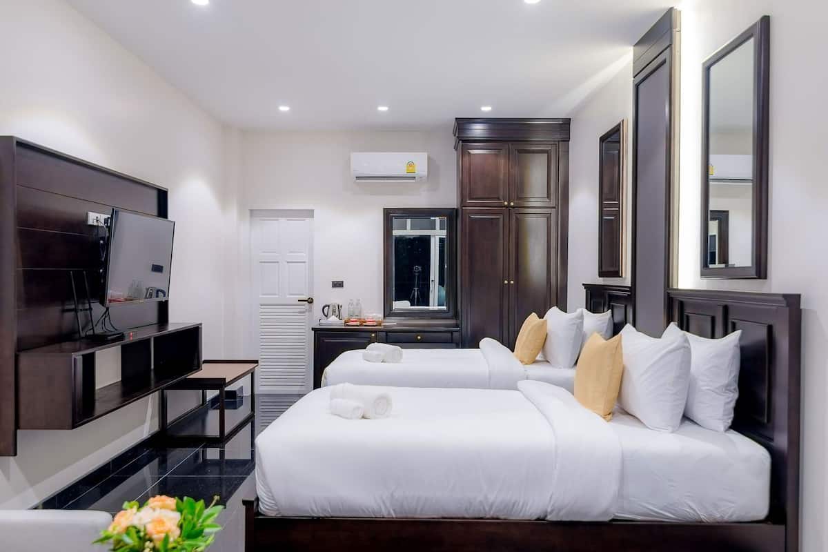 Une chambre d’hôtel avec deux lits, une télévision, un bureau, un miroir et une fenêtre.