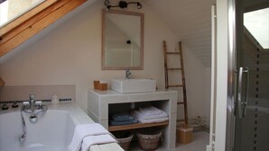 Un baño con bañera, lavabo, espejo y una escalera de madera.