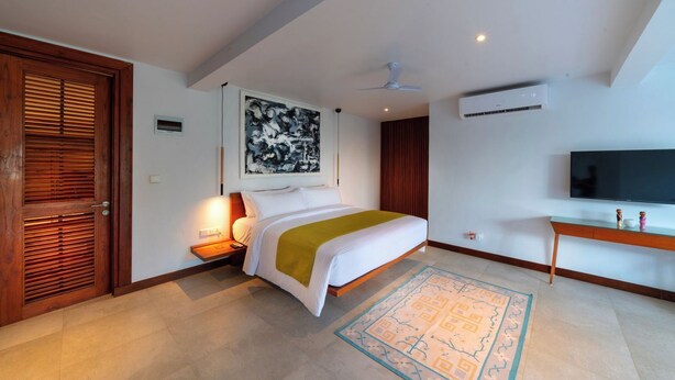 Una habitación de hotel moderna con cama, mesita de noche, televisor y ventilador de techo.