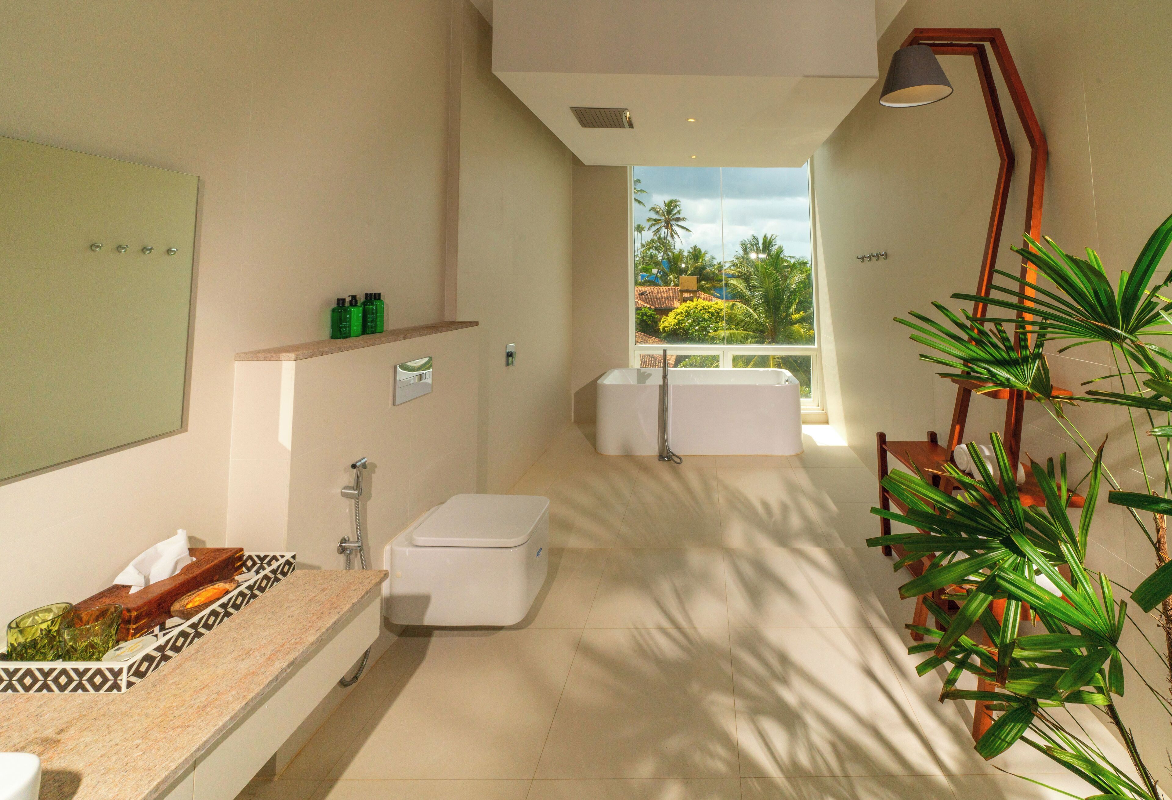 A modern bathroom with a shower, toilet, and sink. There is a shelf with toiletries and a potted plant.