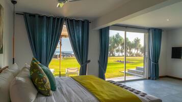 A bedroom with a bed, a ceiling fan, and a view of a grassy area through a glass door.