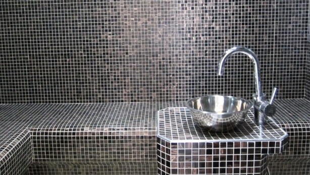 Un baño con piso de azulejos, un lavabo y una pileta de metal.