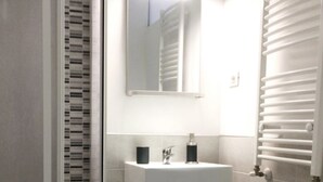 Un baño con un lavamanos blanco, un espejo y un radiador.