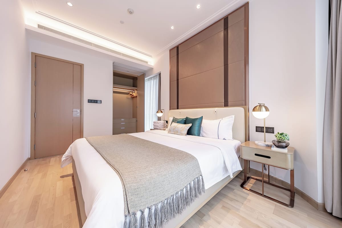 Ein modernes Hotelzimmer mit einem großen Bett, Nachttischen, einem Kleiderschrank und einem begehbaren Kleiderschrank.