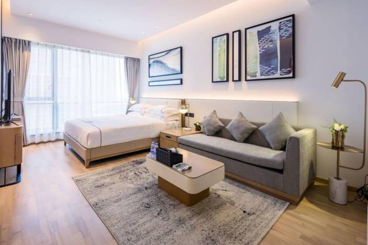 Ein modernes Hotelzimmer mit Bett, Sofa, Couchtisch und Bildern an den Wänden.