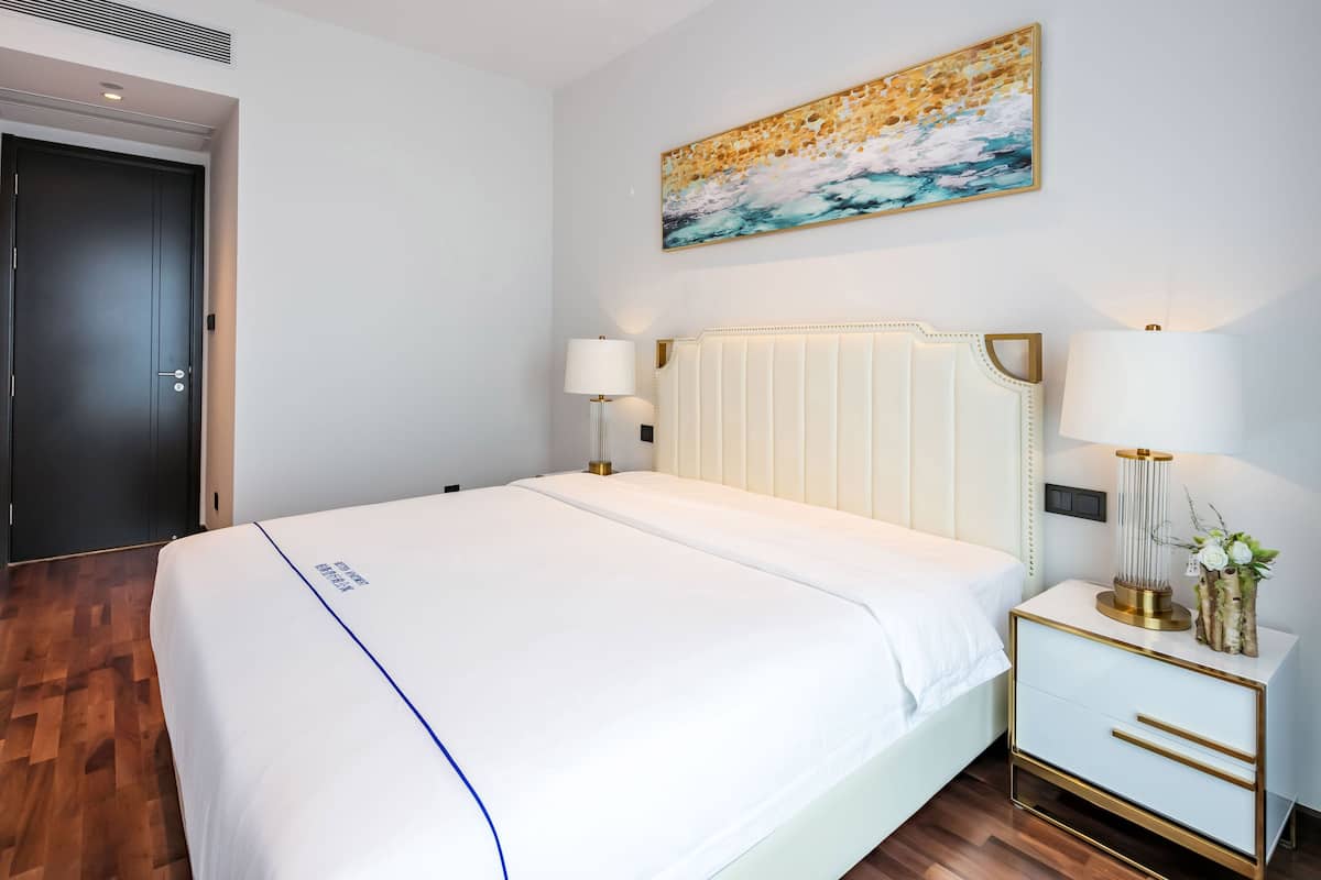 Ein Hotelzimmer mit einem großen Bett, Nachttischlampen, einem Nachttisch und einem Bild an der Wand.