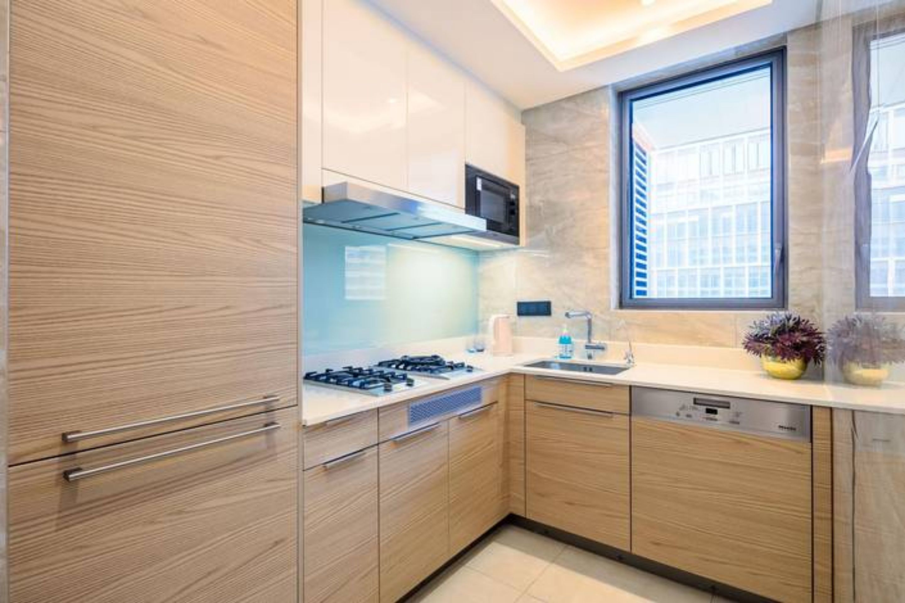 Una cocina moderna con armarios de madera, estufa a gas, microondas y ventana que proporciona luz natural.