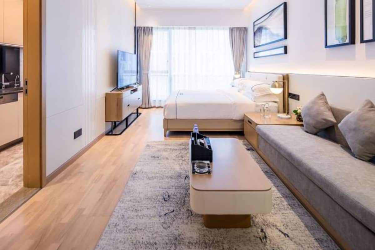 Ein Hotelzimmer mit Bett, Sofa, Fernseher, Schreibtisch und Fenster.