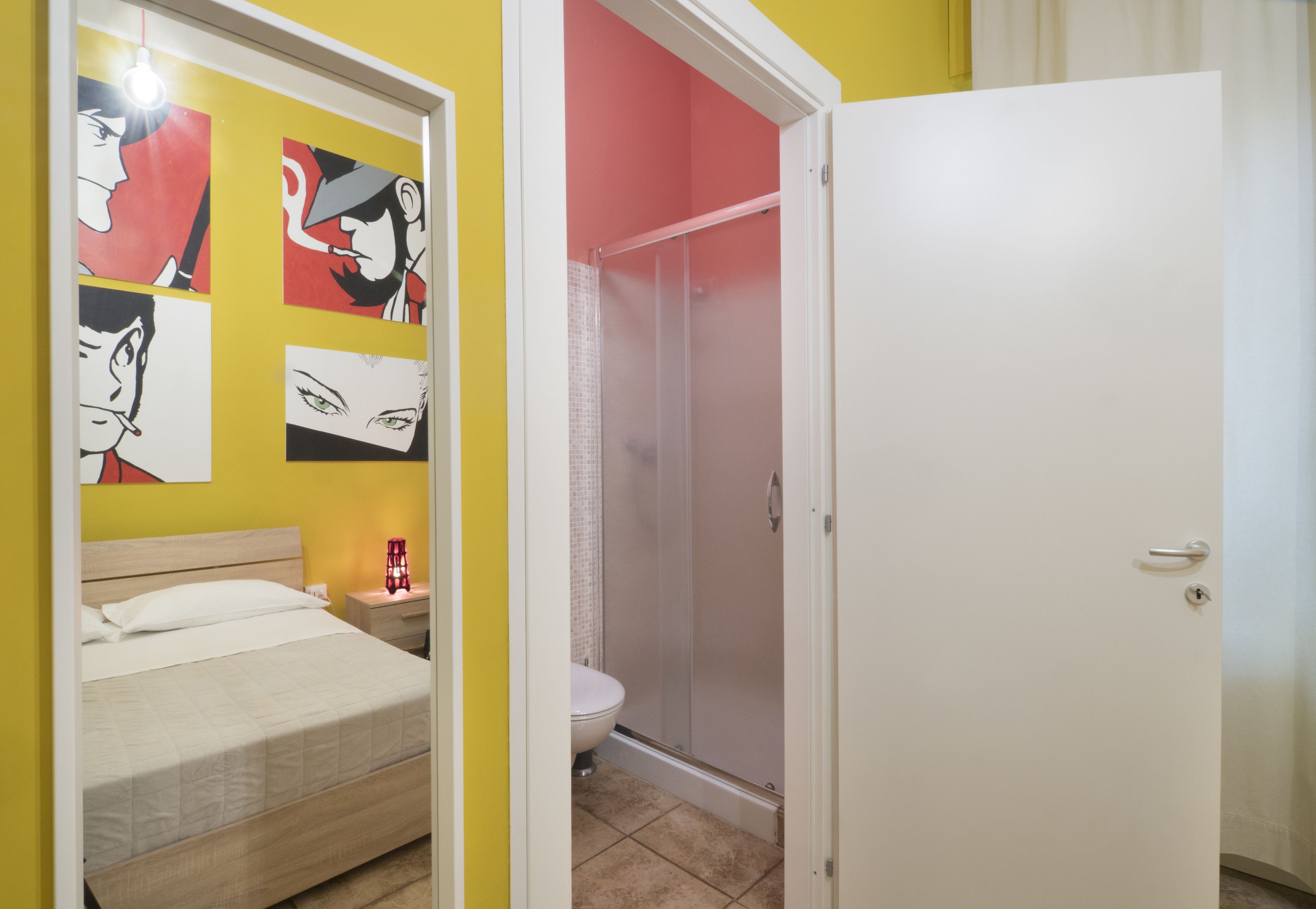A bedroom with a bed, a nightstand, and a wall with artwork.