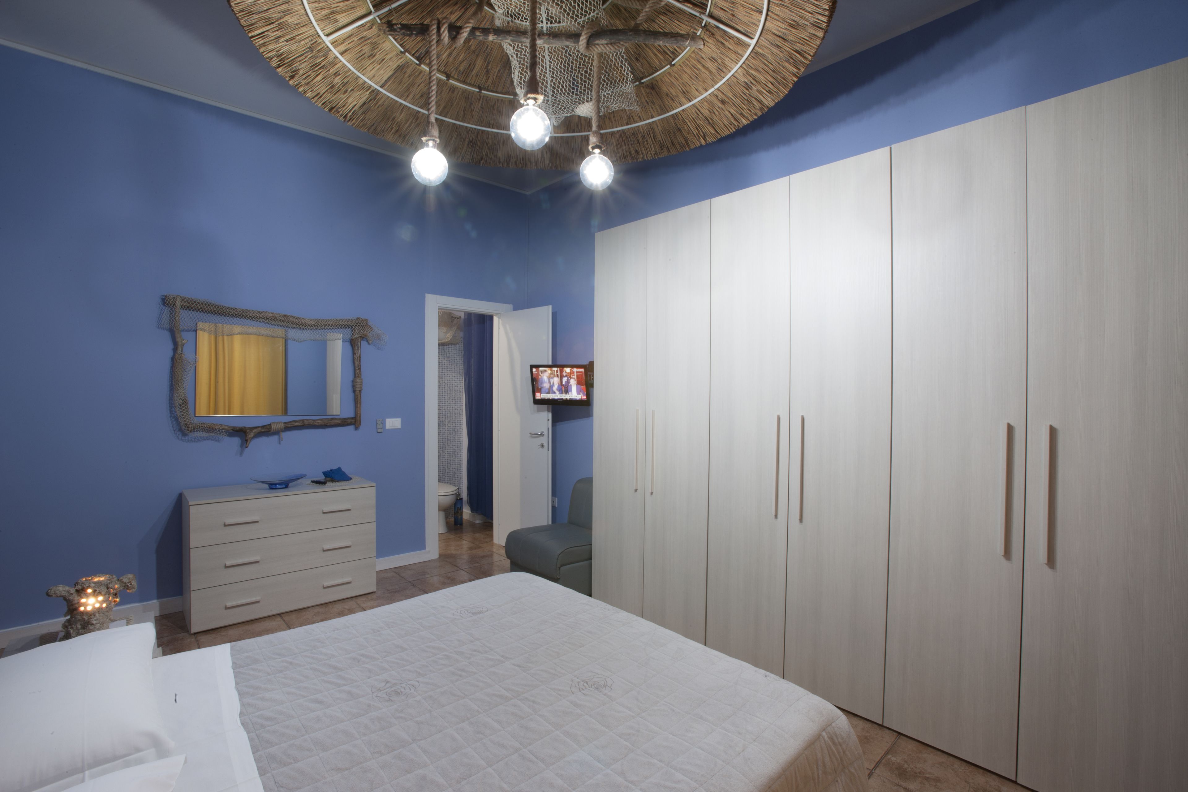 Une chambre à coucher comprenant un lit, une commode, une armoire, un téléviseur et un ventilateur de plafond.