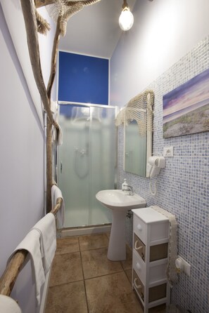 Un baño con ducha de vidrio, lavamanos y espejo.