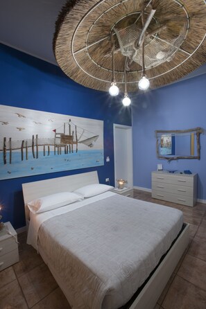 Un dormitorio con cama, mesita de noche, cómoda, cuadro en la pared y ventilador de techo.