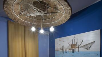 Un dormitorio con cama, mesita de noche, una obra de arte en la pared y ventilador de techo.