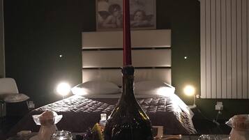 Una habitación de hotel con una cama, una mesita de noche con una botella y una lámpara de pared.