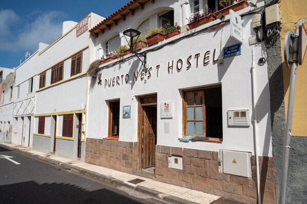 Un hostal con un cartel que dice "Puerto Nuevo Hostel" y una farola sobre la entrada.