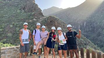 A group of people standing on a rocky path with a mountainous landscape in the background.