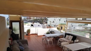 En rummelig terrasse med spisebord, stole og sofa.