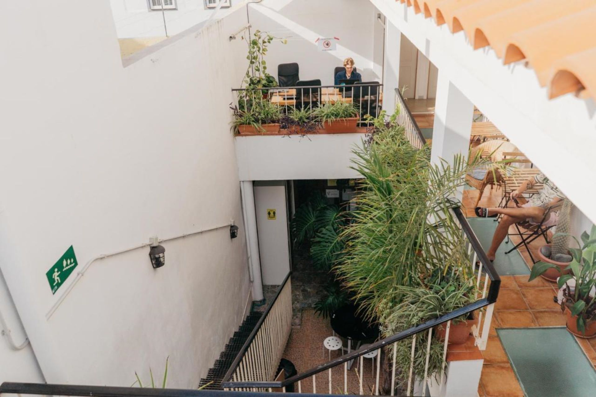 Un espace intérieur à plusieurs niveaux, doté d’un escalier, de plantes en pot et de coins salon.
