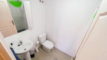 A small, clean bathroom with a white sink, toilet, and mirror.
