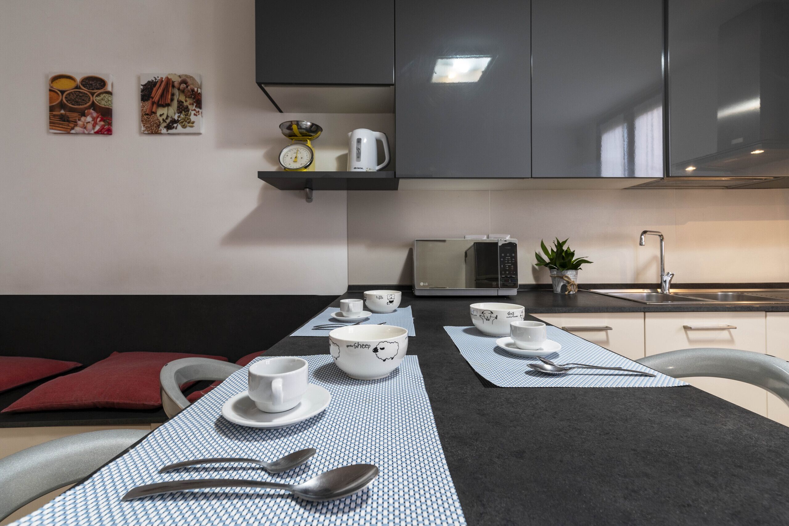 A modern kitchen with a dining table set for four, equipped with bowls, cups, and cutlery.