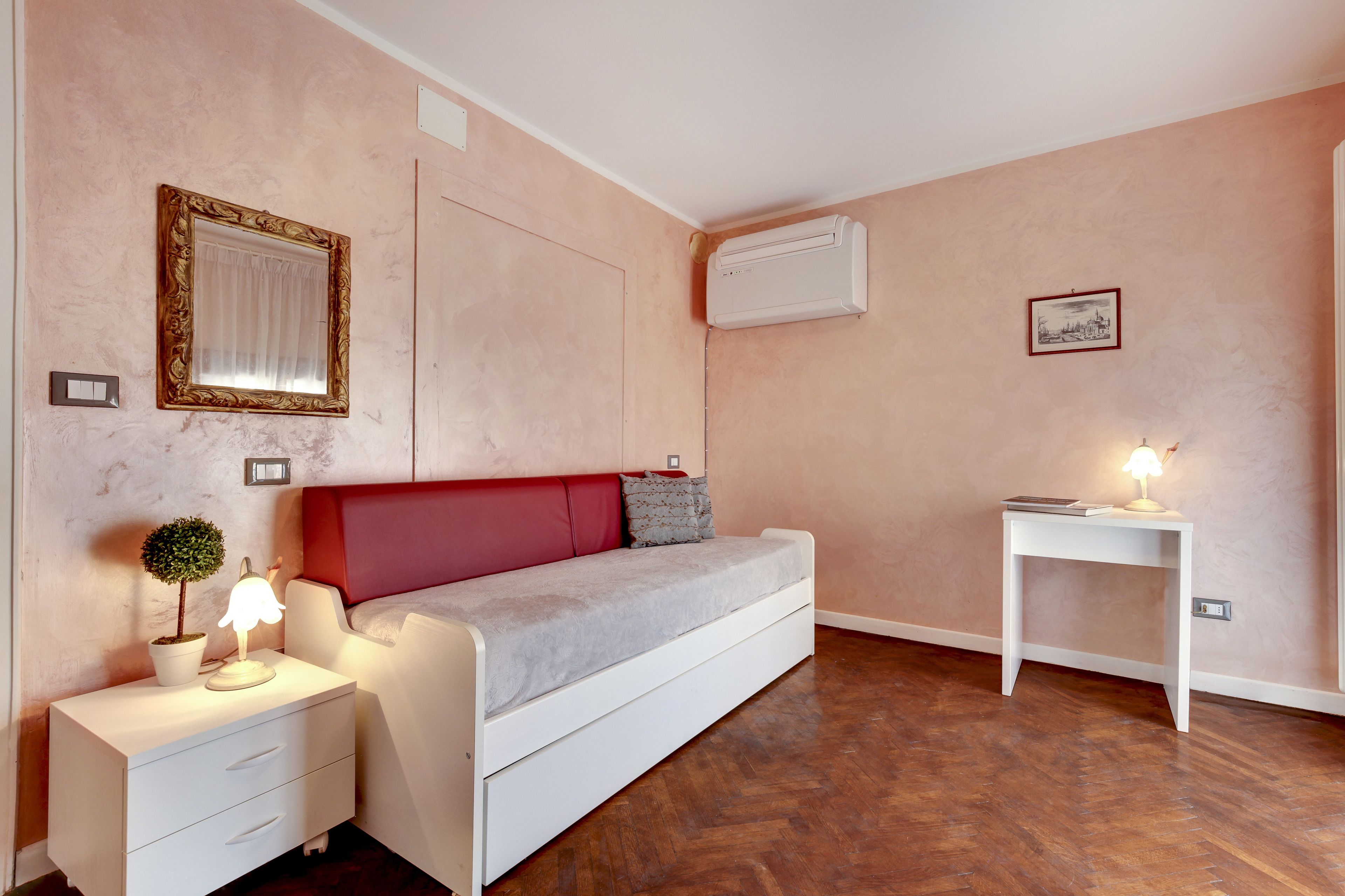 A bedroom with a bed, bedside table, lamp, and a small potted plant.
