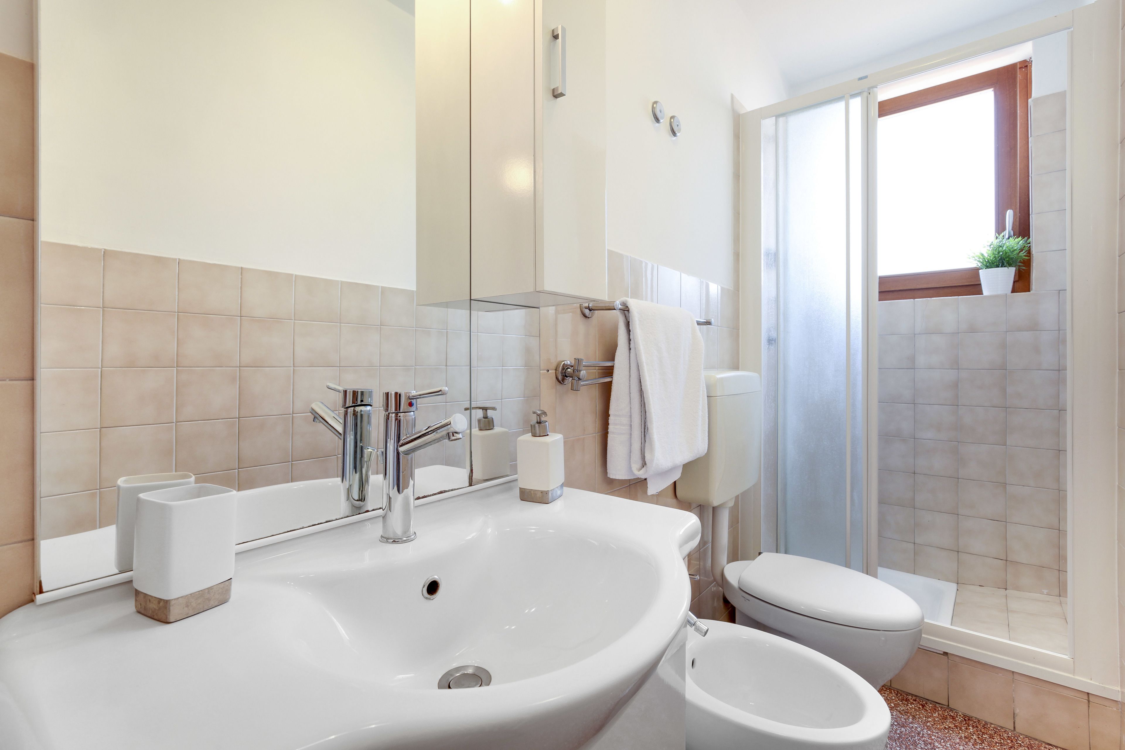 A modern bathroom with a large sink, toilet, and shower area.